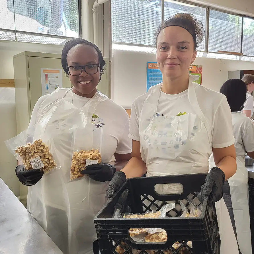 Two volunteers working at one of the Quest Warehouses and smiling at the camera