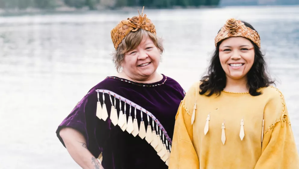 Two female members of the Tsleil-Waututh Nation standing in front of a body of water.