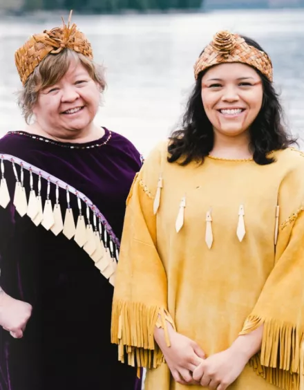 Two female members of the Tsleil-Waututh Nation standing in front of a body of water.